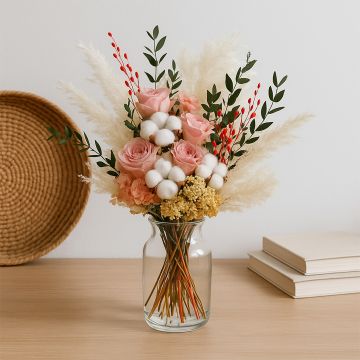 Lifestyle image of preserved flower bouquet with pink roses white cotton stems pampas grass and greenery in a glass vase creating an elegant home decor arrangement.