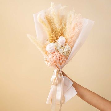 Elegant dried flower bouquet with pampas grass infinity rose hydrangea and babysbreath tied with satin ribbon on plain background.