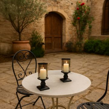 Elegant black glass candle holder with lit candle creating warm cozy ambiance on outdoor patio table.