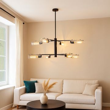 Modern black metal chandelier with clear glass tube shades and Edison bulbs mounted in interior space creating industrial lighting.