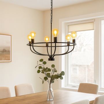 Modern black metal wagon wheel chandelier with amber Edison globe bulbs hanging in interior space creating rustic lighting.
