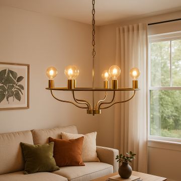 Elegant brass gold wagon wheel chandelier with amber Edison globe bulbs hanging in interior space creating luxurious lighting.