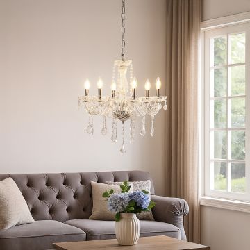 Crystal chandelier with silver accents glowing warmly above sofa in living room for luxury home lighting.