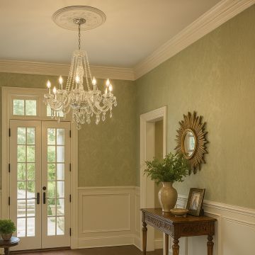 Crystal chandelier with silver finish glowing in elegant entryway interior above console table and wall mirror