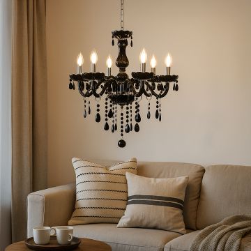 Black chandelier with crystal droplets glowing warmly above sofa in living room for elegant interior lighting.