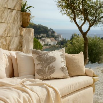 Soft cotton cushion covers with beige botanical embroidery placed on an outdoor sofa offering a warm natural décor mood with breathable gentle and skin friendly fabric suitable for open spaces.