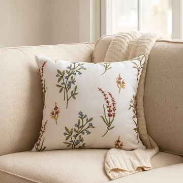 Embroidered floral cushion in soft multicolor thread displayed on a beige sofa creating a cozy elegant decor accent for modern living room interiors.