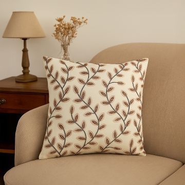 Cotton cushion with brown and beige embroidered leaf pattern placed on a neutral sofa creating a warm cozy lifestyle decor accent for modern living spaces.