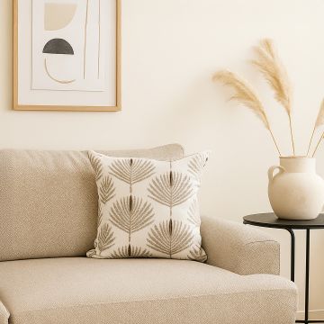 Beige sofa styled with a cream cushion featuring textured leaf embroidery creating a warm natural and elegant lifestyle decor accent in a cozy living room.