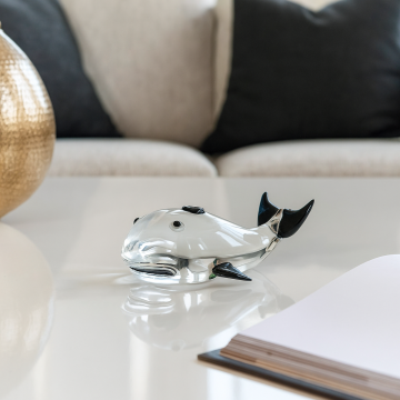 Elegant glass dolphin figurine with black fins placed on wooden table for modern home interior and shelf decor.
