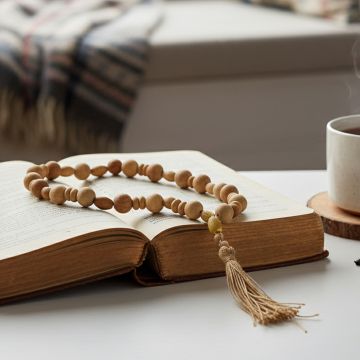 Wood bead garland styled on an open book beside a coffee cup for cozy and warm living room decor.