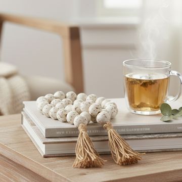 Speckled bead garland placed on stacked books beside a cup of tea creating a soft and cozy home decor vibe.