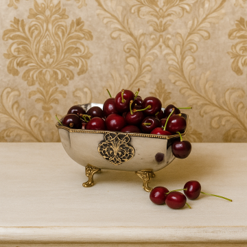 Square stainless steel fruit bowl with gold accents and deep interior shown angled on white background.