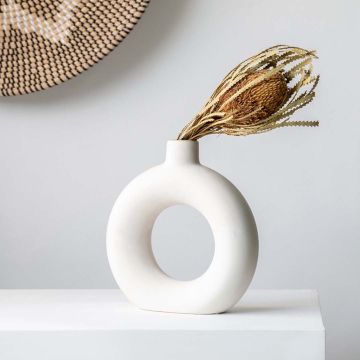 Natural dried banksia flower stem styled in modern white donut ceramic vase creating elegant boho lifestyle home decor.
