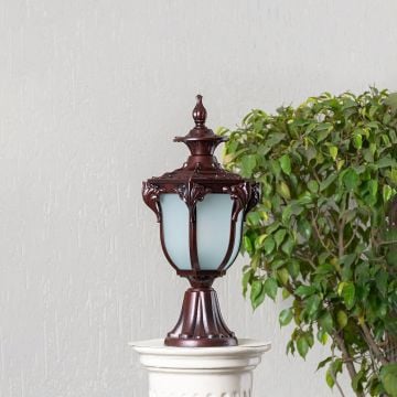 Classic outdoor brown pillar lamp with frosted glass shade and ornate design placed on stone base for garden and patio.