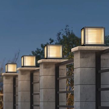 Modern outdoor black pillar lamp with frosted glass glowing warmly on stone wall for gate and garden decor.
