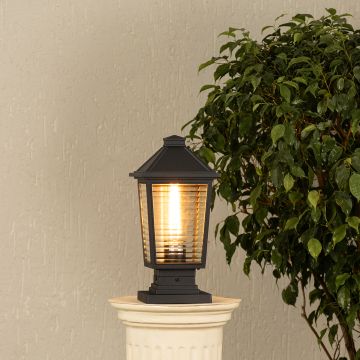 Black outdoor post light with lantern style design on a pillar Lifestyle image warm ambient porch lighting.