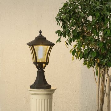 Black outdoor pillar lantern with light on placed on a decorative pedestal creating warm ambient glow with textured glass and classic metal frame for garden decor.