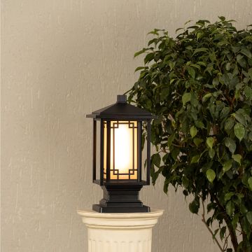 Black metal outdoor post lantern Light On mounted on a stone pillar Traditional garden gate lighting Main Lifestyle image at night.
