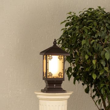 Black metal outdoor post lantern Light On mounted on a stone pillar Traditional garden gate lighting Main Lifestyle image at night.