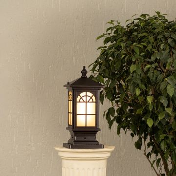 Black metal outdoor post lantern Light On mounted on a stone pillar Traditional garden gate lighting Main Lifestyle image at night.
