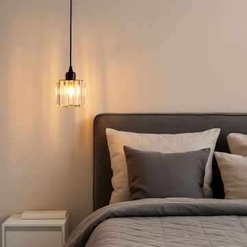 Glass pendant light with black finish glowing warmly above bedside table in modern bedroom decor.