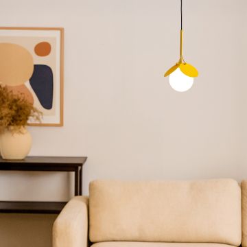 Pendant light with yellow frame and frosted globe glowing in modern living room decor above beige sofa.