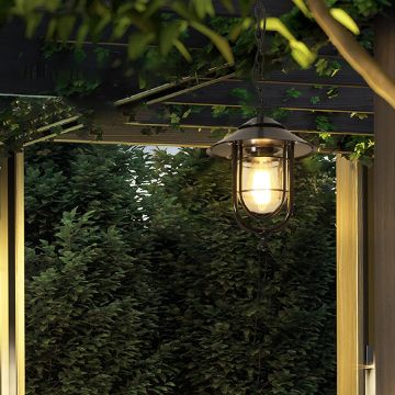 A warm outdoor seating corner with a hanging lantern casting a soft glow above lush greenery and a wooden pergola creating a cozy evening ambiance.