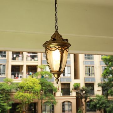 Elegant antique gold metal hanging lantern glowing softly on a balcony setting for warm outdoor lighting decor.
