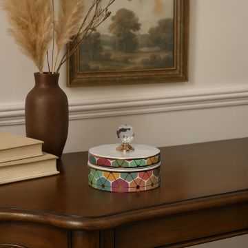 Small multicolor geometric ceramic jar with crystal knob lid styled on table adding artistic touch to home decor.