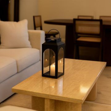 Black metal lantern with candle lit creating cozy warm glow for living room coffee table evening decor.