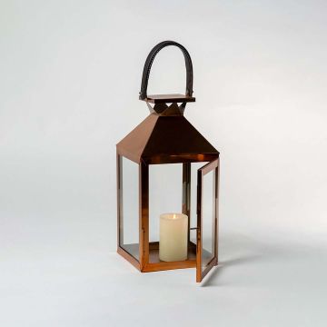 Bronze lantern with glass panels photographed against a white background with door open to reveal interior candle space highlighting product craftsmanship and metallic finish.