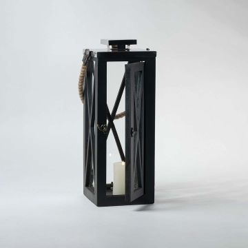 Black lantern illuminated on a white background showcasing the glow through its transparent glass windows.