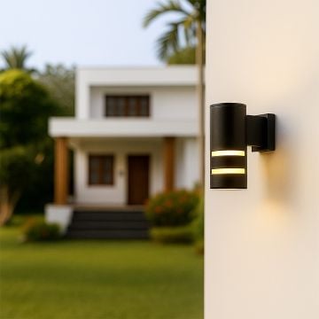 Modern black cylindrical wall light brightening an outdoor space with soft glow and sleek dual-ring design.