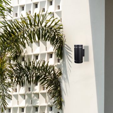 Modern ribbed black wall light brightening up exterior walls with a warm glow and stylish appeal.
