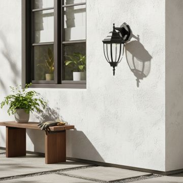 Black downward outdoor wall lantern with curved glass creating classic vintage coach style lighting for home exterior decor.