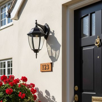 Black downward outdoor wall lantern with clear glass creating classic vintage coach style lighting for traditional exterior.