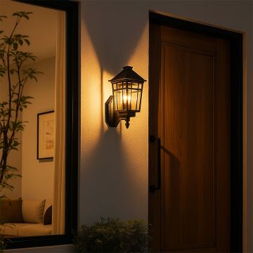 A classic outdoor wall lantern glowing with warm light beside a wooden door creating a welcoming entrance ambience for evening home exteriors and pathways.