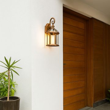 Warm glowing antique gold outdoor wall lantern mounted beside a wooden door adding elegant exterior lighting to a modern home entrance wall.