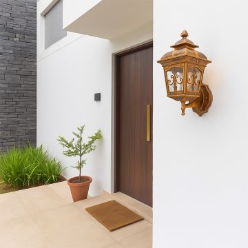 Elegant outdoor wall lantern in a warm gold finish glowing softly at a modern home entrance creating a welcoming ambiance in the exterior setting.