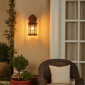 Bronze outdoor wall lantern with the light on casting a warm glow on a textured exterior wall creating a cozy and inviting ambiance for porch and patio spaces.