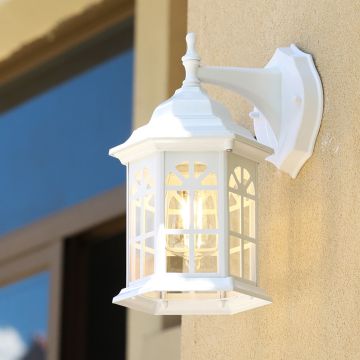White outdoor wall lantern with the light on mounted against a textured exterior wall creating a warm welcoming glow for porch patio and entrance styling.