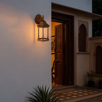 A warm outdoor scene featuring a golden wall lantern light ON casting a soft glow near an entrance surrounded by plants creating a welcoming evening ambiance.