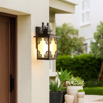 Warm glowing brown metal outdoor lantern mounted beside a door adding inviting ambient lighting with frosted glass and decorative detailing to exterior walls.