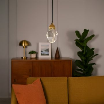 Crystal pendant light with golden holder illuminating cozy living room creating a warm and luxurious ambience.