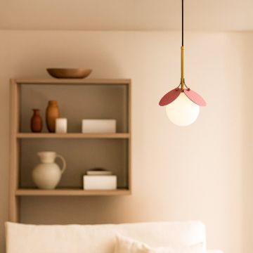 Modern pendant light with pink decorative shade gold holder and frosted glass globe styled in cozy living room interior.