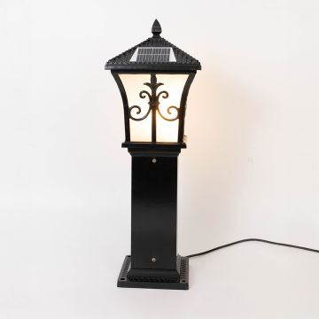 A solar garden lamp with warm light on displayed against a white background showing its decorative black frame and frosted panels in a clear product view.