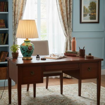Green floral ceramic table lamp with white pleated shade placed on study desk adding elegance to interior lighting.