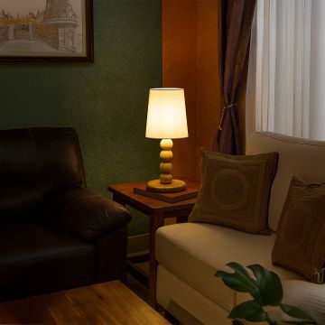 Modern table lamp with tall white shade and stacked light wood base adding warm ambient lighting that enhances stylish contemporary interior home decor settings.