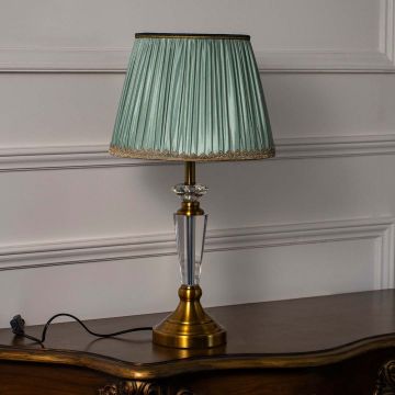 Classic table lamp with mint pleated shade and brass base placed on white wall background for an elegant vintage look.